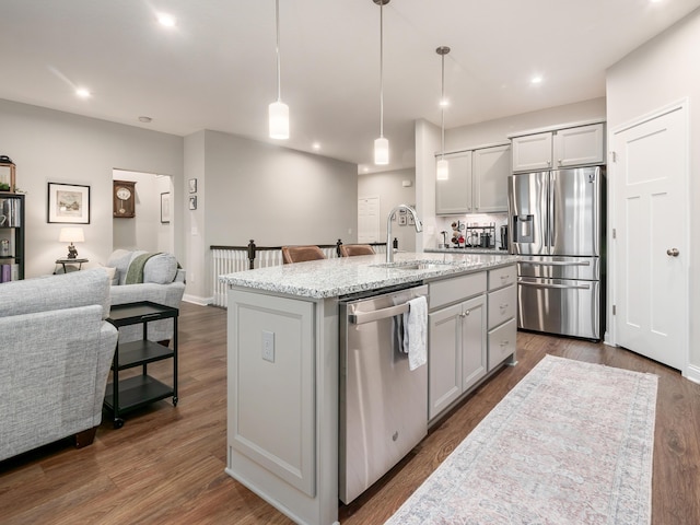 kitchen with pendant lighting, sink, stainless steel appliances, and a kitchen island with sink