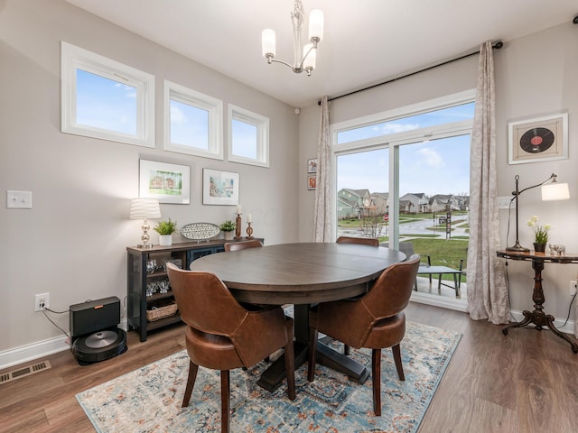 dining space with hardwood / wood-style flooring, an inviting chandelier, and a healthy amount of sunlight