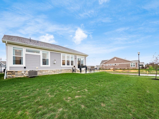 rear view of house featuring a lawn and central air condition unit