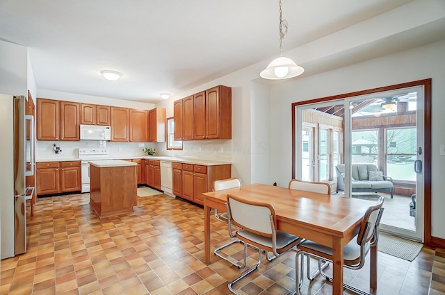 kitchen with backsplash, a kitchen island, hanging light fixtures, and white appliances