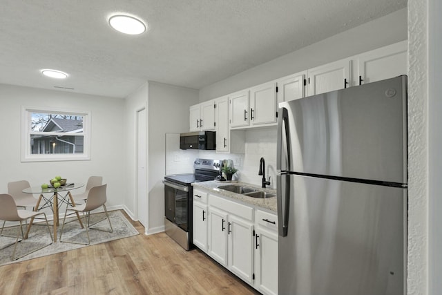 kitchen featuring sink, white cabinetry, stainless steel appliances, and light hardwood / wood-style flooring