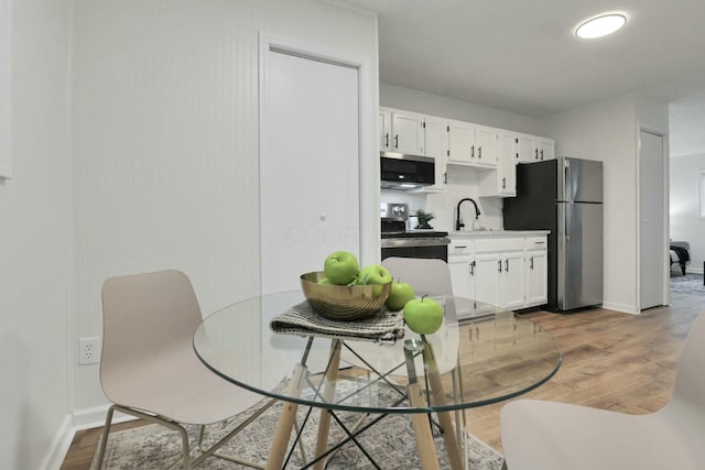 kitchen featuring hardwood / wood-style floors, stainless steel appliances, white cabinetry, and sink