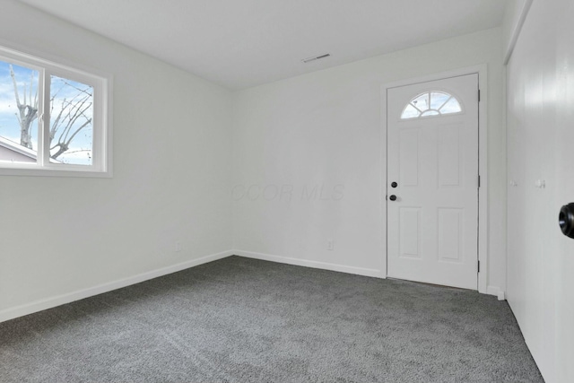 foyer entrance featuring dark colored carpet