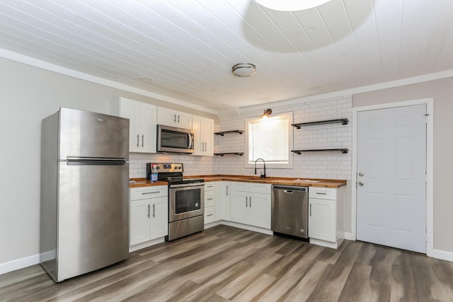 kitchen featuring wooden counters, stainless steel appliances, white cabinets, and sink