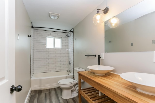 full bathroom featuring vanity, hardwood / wood-style floors, tiled shower / bath, and toilet