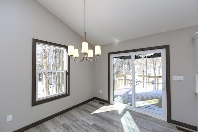 unfurnished dining area featuring hardwood / wood-style flooring, vaulted ceiling, and a notable chandelier