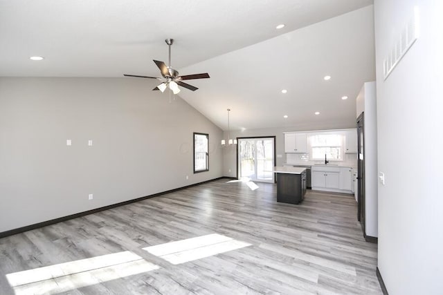 unfurnished living room with ceiling fan, light hardwood / wood-style flooring, high vaulted ceiling, and sink