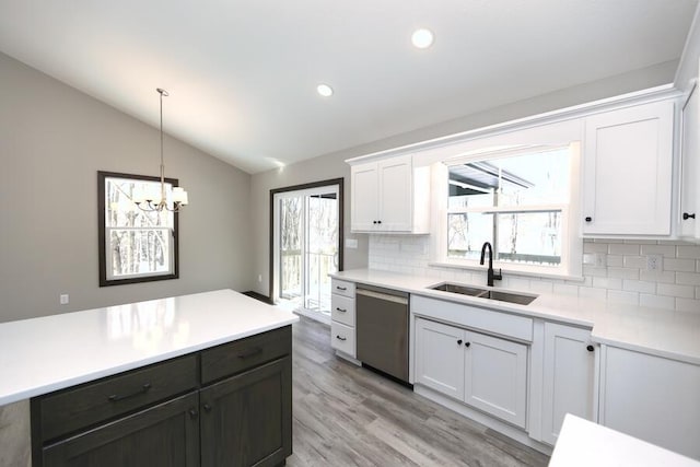 kitchen featuring white cabinetry, sink, stainless steel dishwasher, and vaulted ceiling