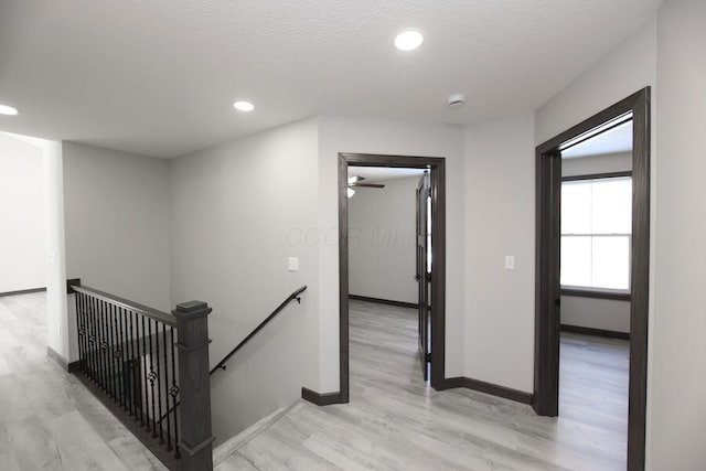 corridor with light hardwood / wood-style flooring and a textured ceiling