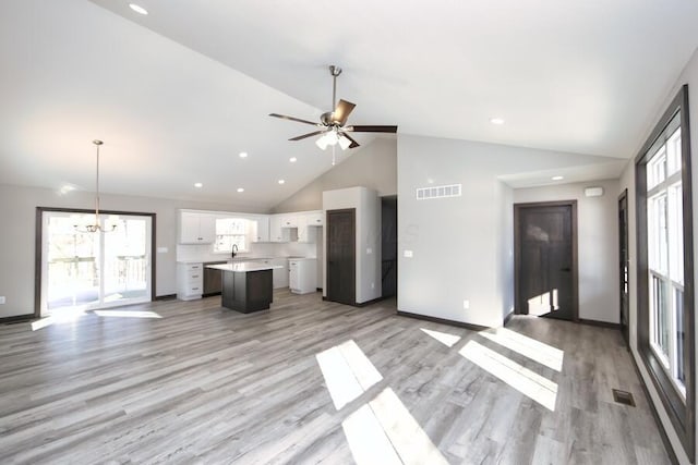 unfurnished living room with sink, high vaulted ceiling, ceiling fan with notable chandelier, and light wood-type flooring