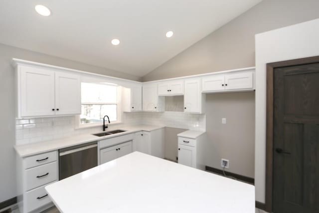 kitchen featuring dishwasher, sink, white cabinets, and vaulted ceiling