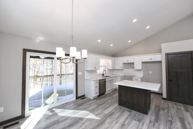 kitchen with backsplash, white cabinets, hanging light fixtures, stainless steel dishwasher, and a kitchen island