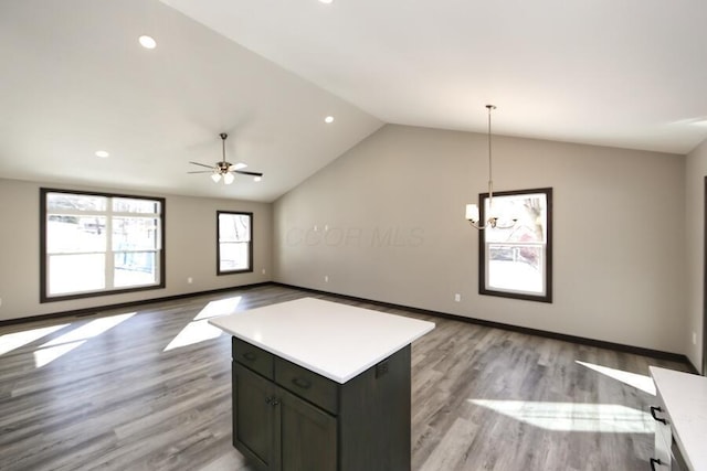 kitchen with a center island, light hardwood / wood-style flooring, vaulted ceiling, decorative light fixtures, and ceiling fan with notable chandelier