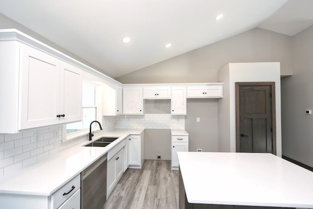 kitchen with sink, tasteful backsplash, stainless steel dishwasher, vaulted ceiling, and white cabinets