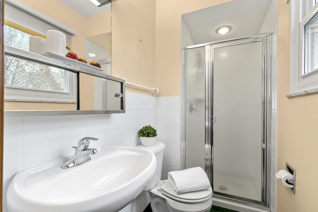 bathroom with an enclosed shower, sink, a wealth of natural light, and tile walls