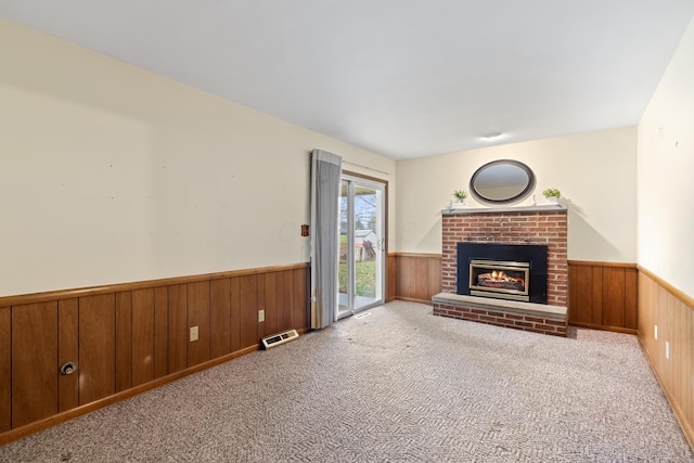 unfurnished living room with a fireplace, light carpet, and wooden walls