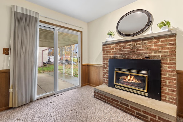 interior space featuring carpet flooring, wood walls, and a brick fireplace