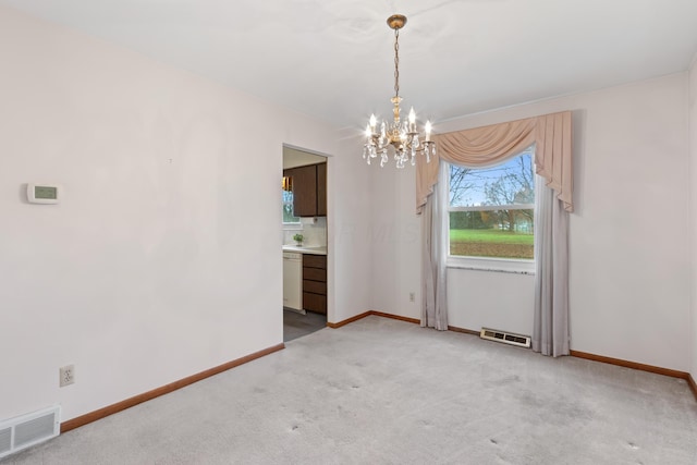 empty room featuring light carpet and a chandelier