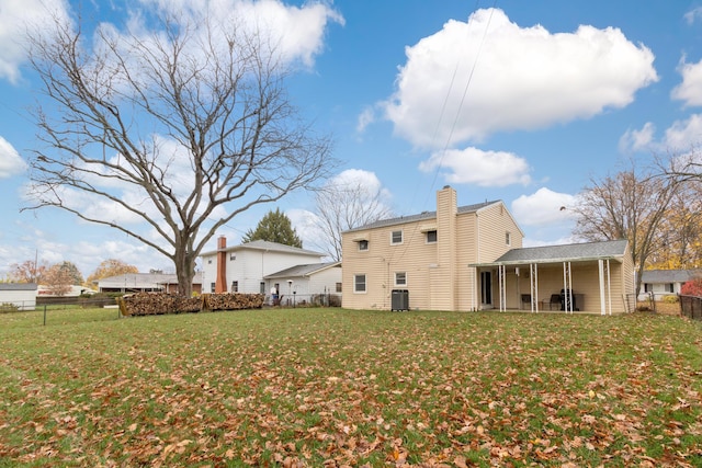 rear view of property featuring central AC and a lawn