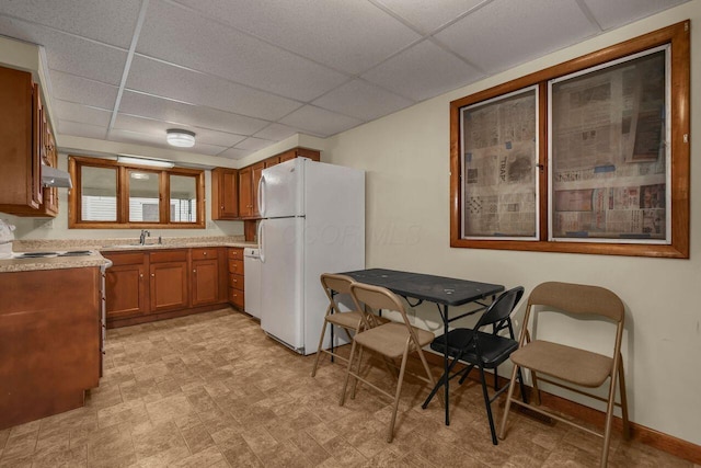 kitchen with white refrigerator, a drop ceiling, and sink