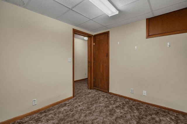 spare room featuring a paneled ceiling and carpet flooring