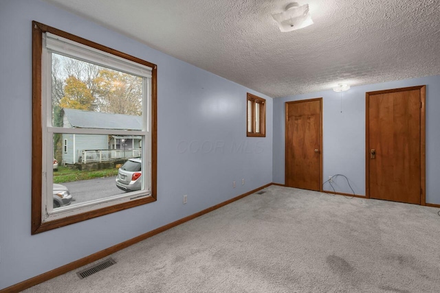 carpeted empty room featuring a textured ceiling