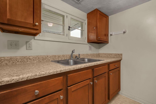 kitchen with a textured ceiling, light tile patterned floors, and sink