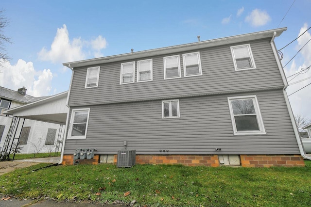 rear view of property featuring a yard and cooling unit