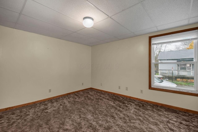 carpeted spare room featuring a drop ceiling