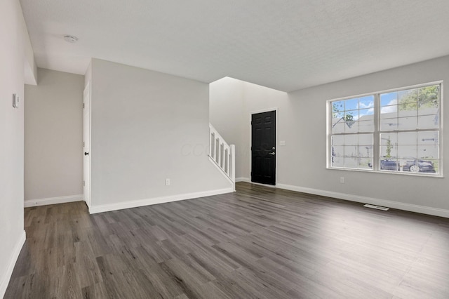 unfurnished living room featuring a textured ceiling and dark hardwood / wood-style floors