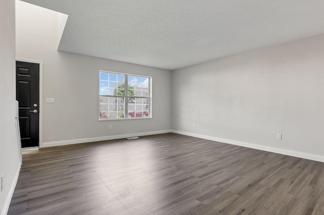 unfurnished room with dark hardwood / wood-style flooring and a textured ceiling