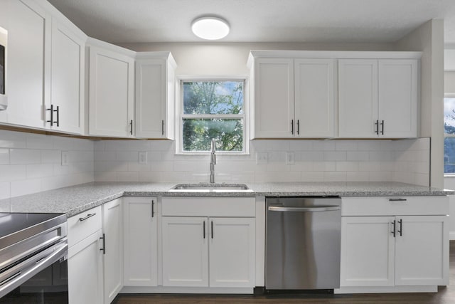 kitchen featuring sink, dark hardwood / wood-style floors, decorative backsplash, appliances with stainless steel finishes, and white cabinetry