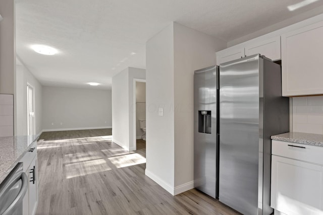 kitchen featuring light stone countertops, white cabinetry, light hardwood / wood-style floors, and appliances with stainless steel finishes