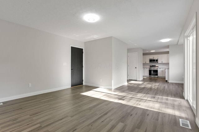 unfurnished living room featuring a wealth of natural light, a textured ceiling, and light wood-type flooring