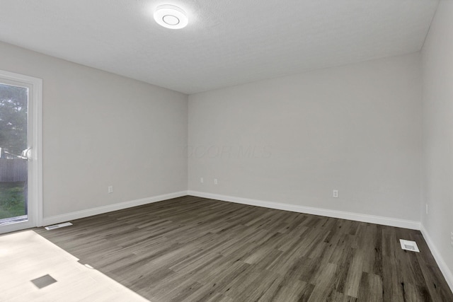 spare room with a textured ceiling and dark hardwood / wood-style flooring