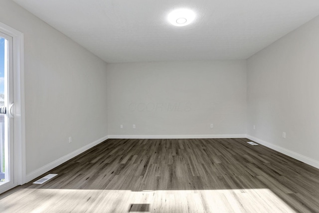 spare room featuring plenty of natural light and dark wood-type flooring