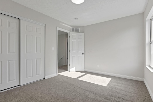 unfurnished bedroom with a closet, carpet floors, and a textured ceiling