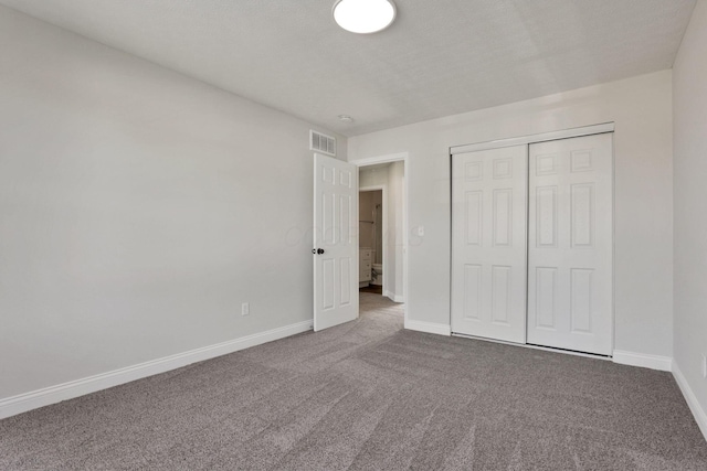 unfurnished bedroom featuring a textured ceiling, carpet floors, and a closet