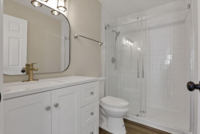 bathroom featuring hardwood / wood-style flooring, vanity, toilet, and a shower with door