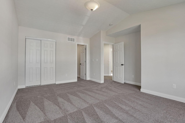 unfurnished bedroom with a closet, carpet, and vaulted ceiling