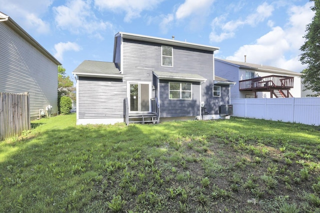 back of house featuring a lawn and central air condition unit