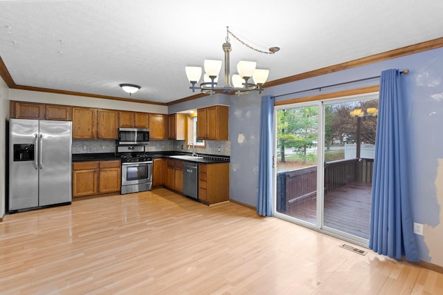 kitchen with tasteful backsplash, hanging light fixtures, appliances with stainless steel finishes, and a chandelier