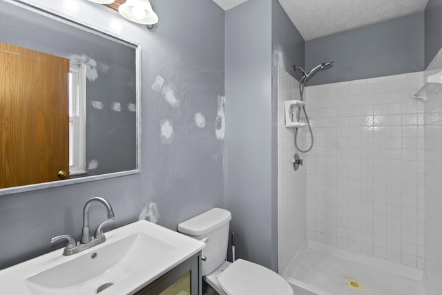 bathroom featuring tiled shower, vanity, a textured ceiling, and toilet