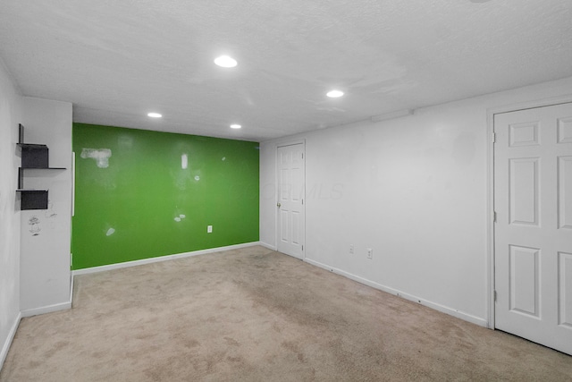 spare room with light colored carpet and a textured ceiling