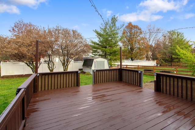 wooden terrace featuring a lawn and a storage unit