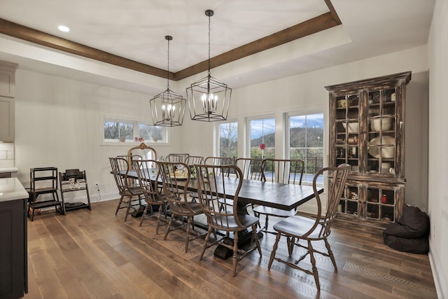 dining area with a raised ceiling, a chandelier, and dark hardwood / wood-style floors