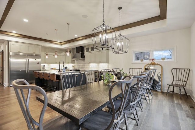 dining space with a tray ceiling, dark wood-type flooring, and a notable chandelier