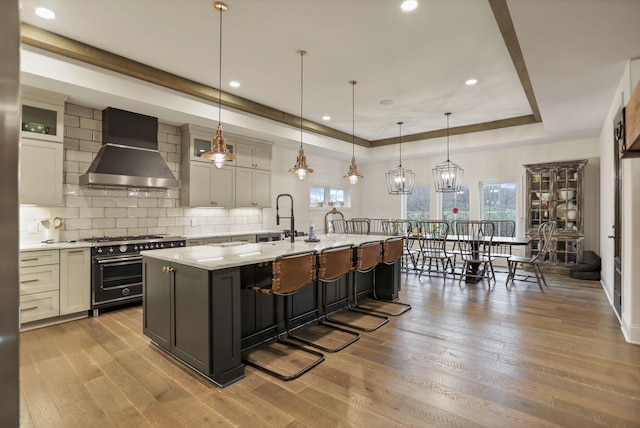 kitchen with stainless steel range, pendant lighting, plenty of natural light, and wall chimney exhaust hood