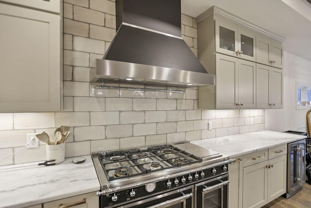 kitchen featuring light stone countertops, high end stainless steel range oven, wall chimney range hood, dark hardwood / wood-style flooring, and backsplash