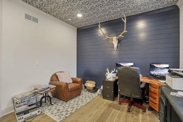 office space with wooden walls, light hardwood / wood-style floors, and ornamental molding